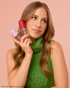 The Grinch x Kitsch Cindy-Lou Duo bottles held to the face by a model in green