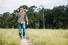 Drake 8 Shot Flyweight long-sleeve shirt in Bottomland camo, worn by man walking a field path