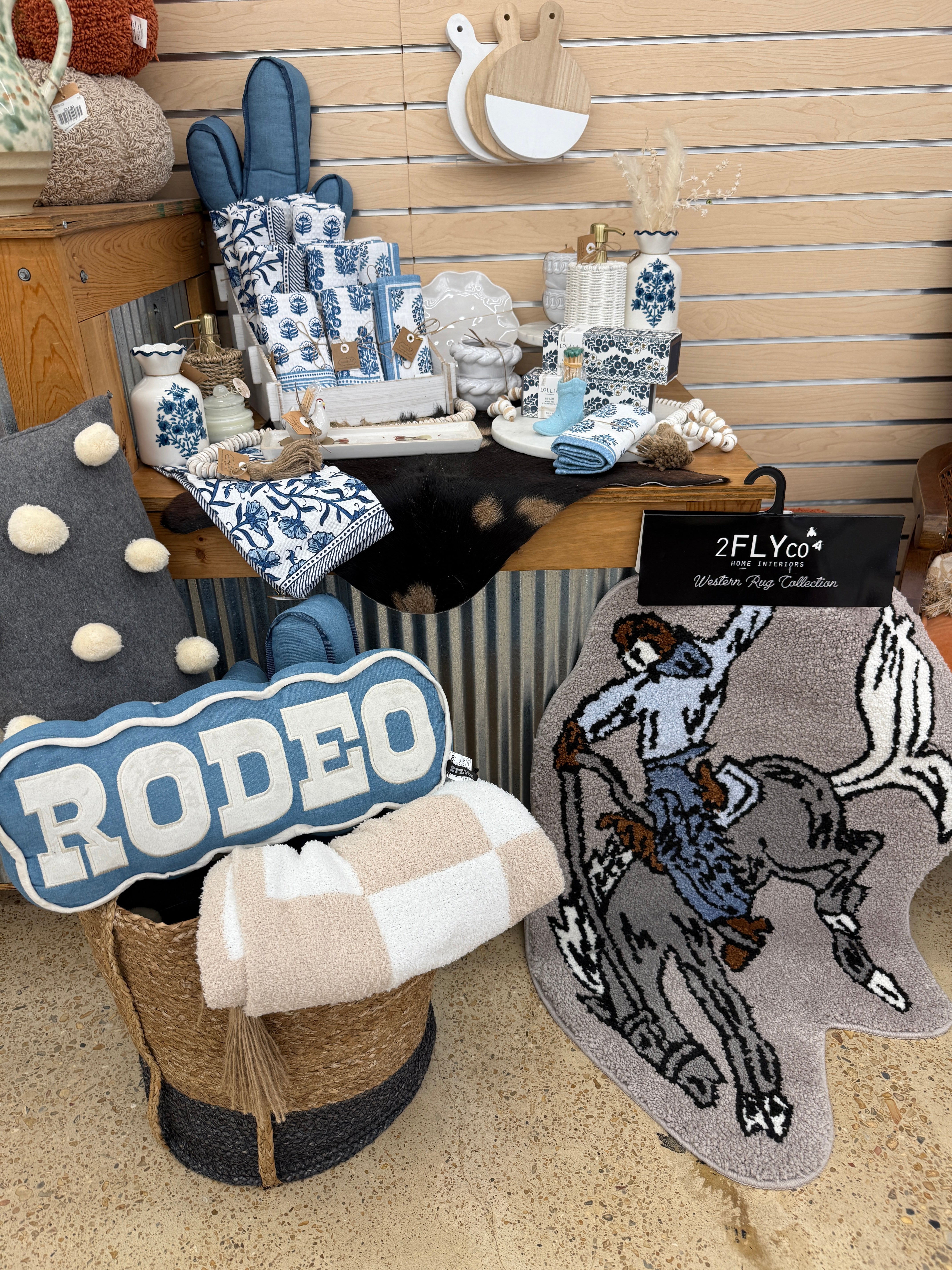 2 Fly Co cactus pillow in blue on a store display with Rodeo pillow