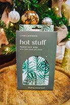 Lemon Lavender Hot Stuff Heated Neck Wrap in green leaf print, boxed by a Christmas tree