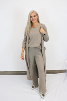 Woman wearing a beige outfit with a long cardigan against a white background