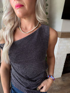 Close-up of the Dear John Nyx silver top showing its shimmering texture, asymmetric neckline and draped waist.