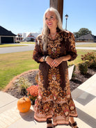 Model in a brown floral print midi dress featuring a ruffle stand collar and bracelet stack