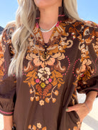 Close-up of the ruffle stand collar, split button neckline and puff sleeve on a brown floral dress