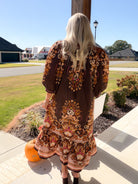 Back view of a brown border floral print midi dress with 3/4 puff sleeves and ruffle hem