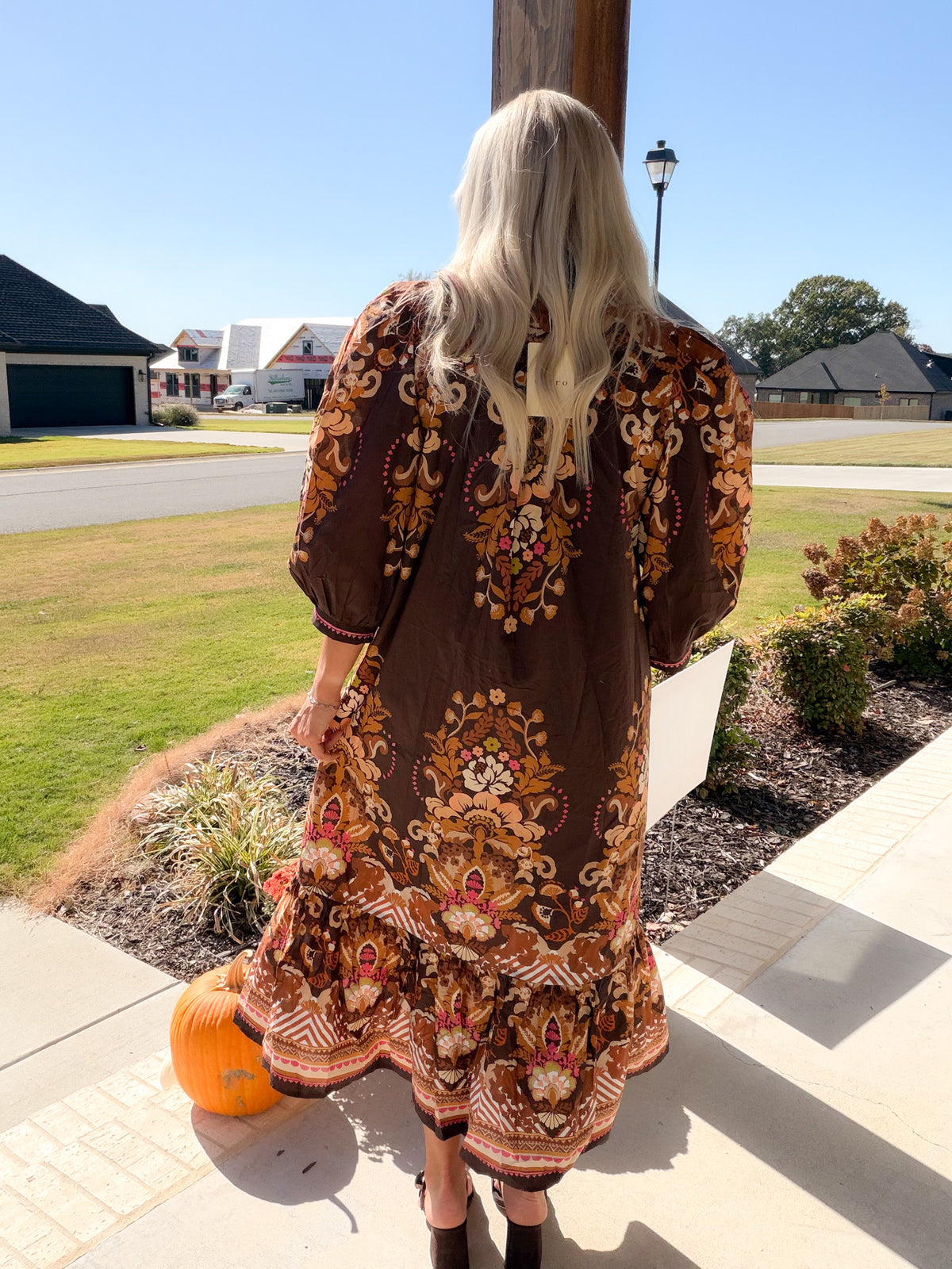 Back view of a brown border floral print midi dress with 3/4 puff sleeves and ruffle hem