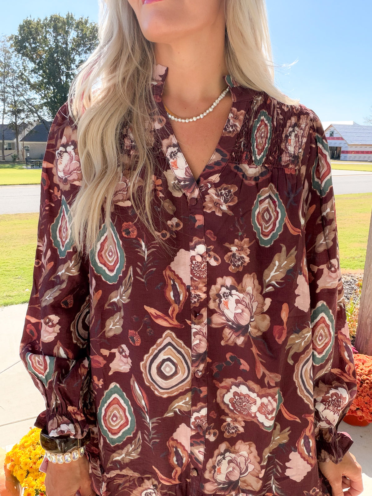 Close-up of merlot floral dress showing V-neckline, button front, and smocked shoulder yoke