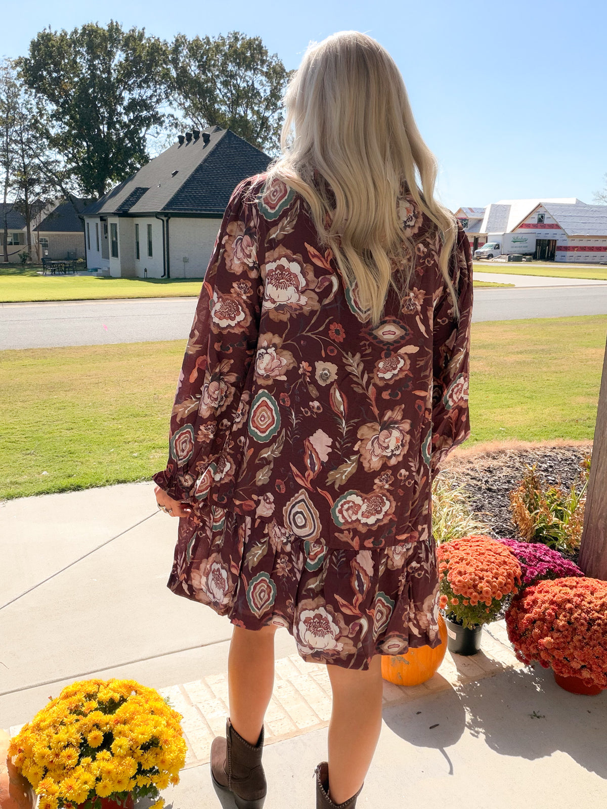 Back view of merlot floral long sleeve dress showing allover print and gathered ruffle hem