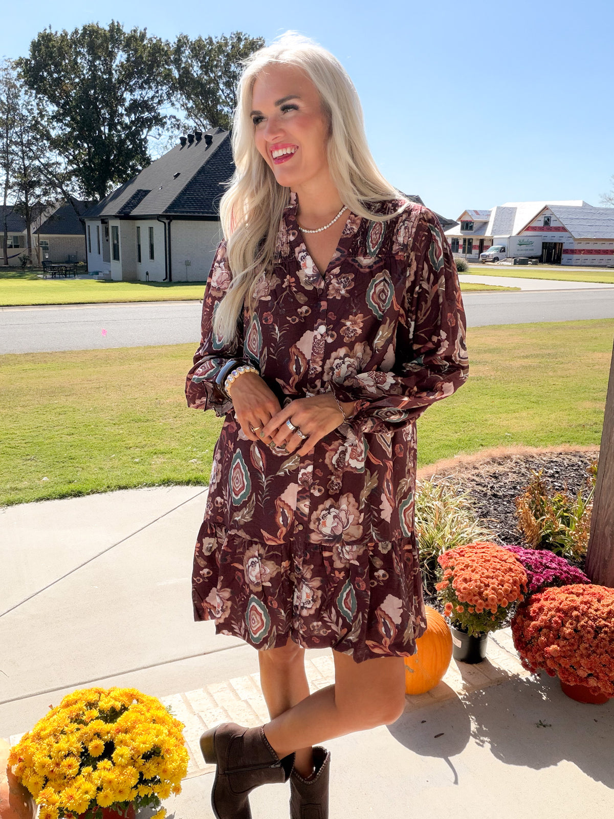 Merlot floral button-down dress with long gathered sleeves and ruffled hem, model with hands at waist