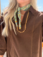 Close-up of brown cotton corduroy dress showing collar, contrast scalloped neckline trim, and ribbed texture