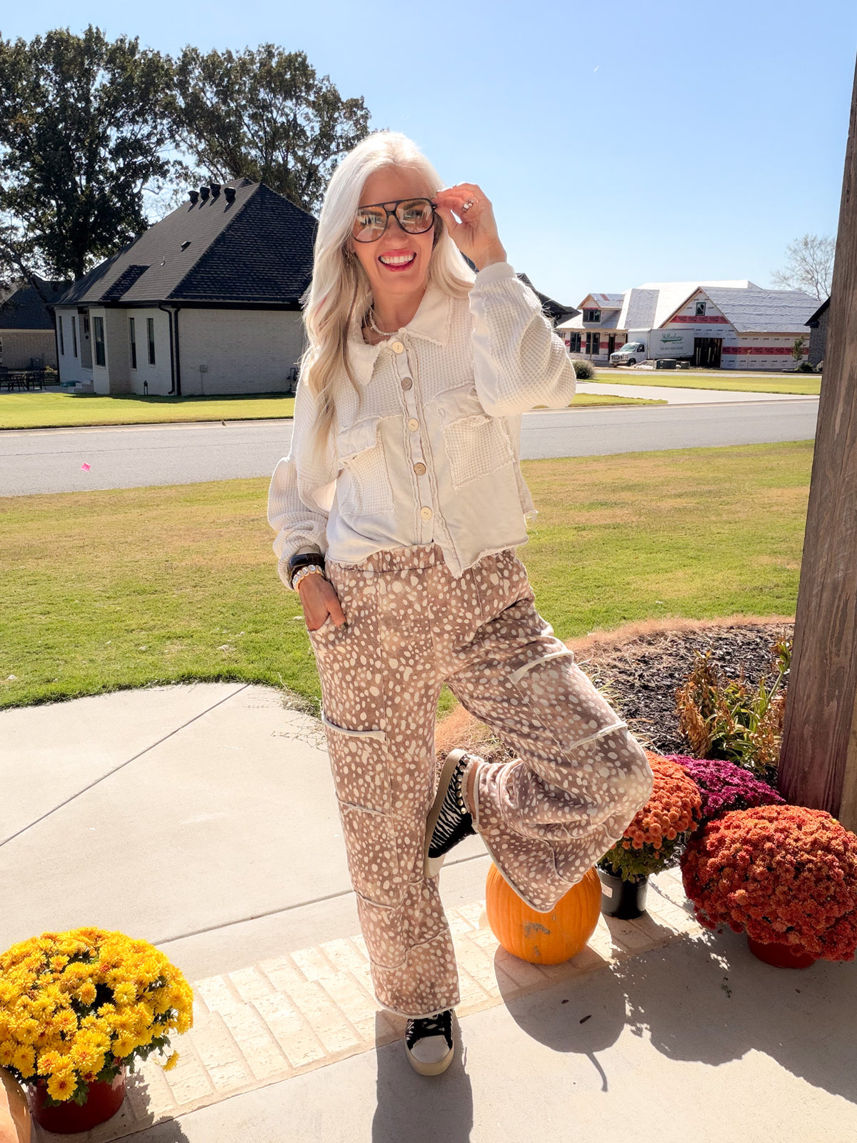 Full outfit with a natural button-front short shacket, printed wide-leg pants, and black high-top sneakers.