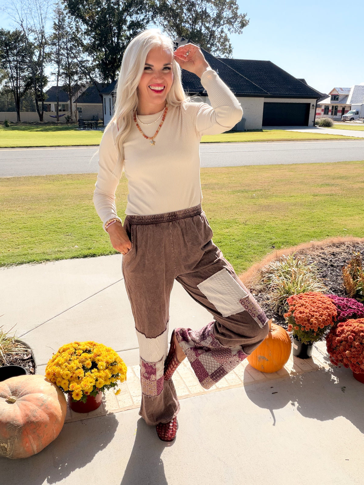 Natural ribbed long sleeve top tucked into brown patchwork pants, styled with layered necklaces and red clogs