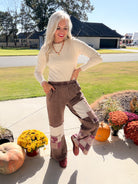 Model lifting one leg in chocolate paisley patchwork pants, showing the wide-leg cut and contrasting panels.