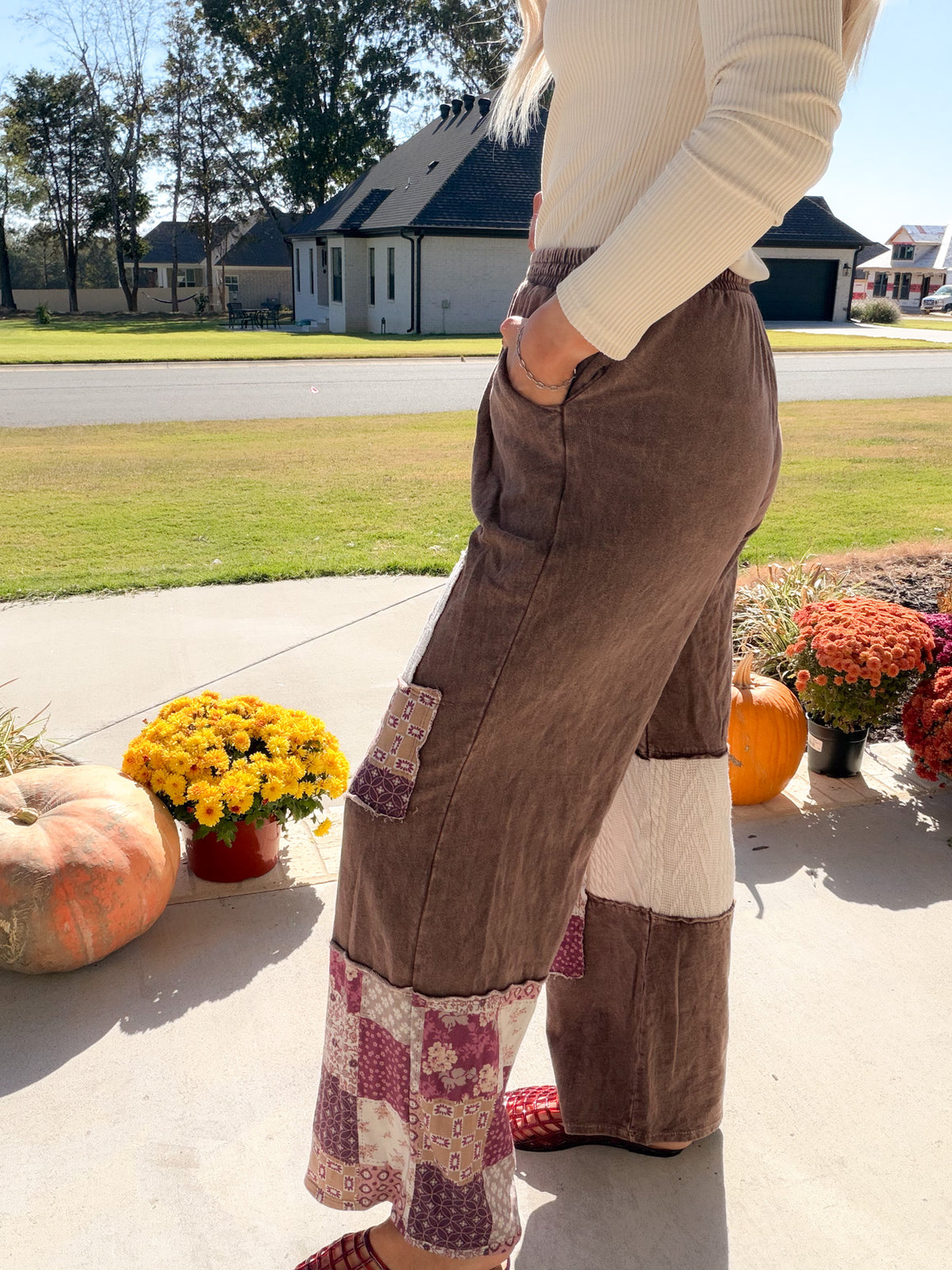 Side view of mineral-washed chocolate patchwork pants showing a side pocket and paisley hem panel.