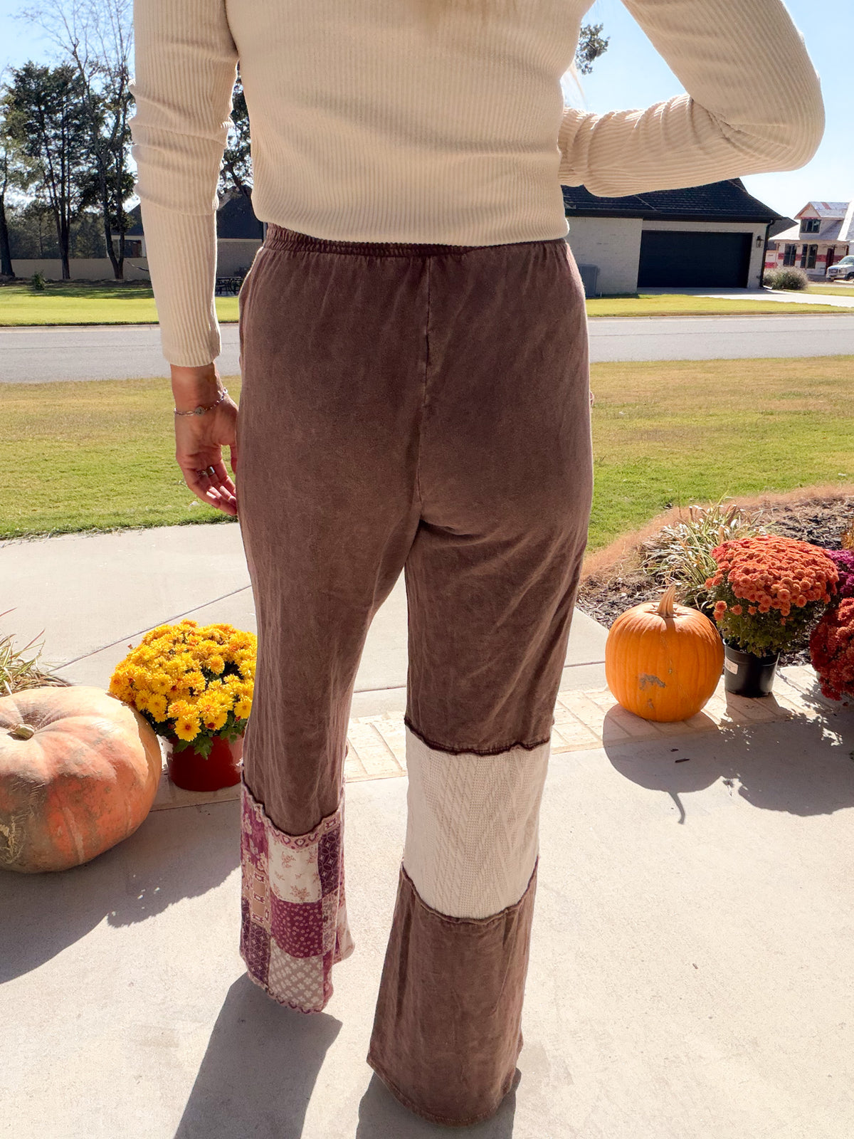 Back view of chocolate wide-leg pants with an elastic waistband, cream panel and paisley patchwork hem.