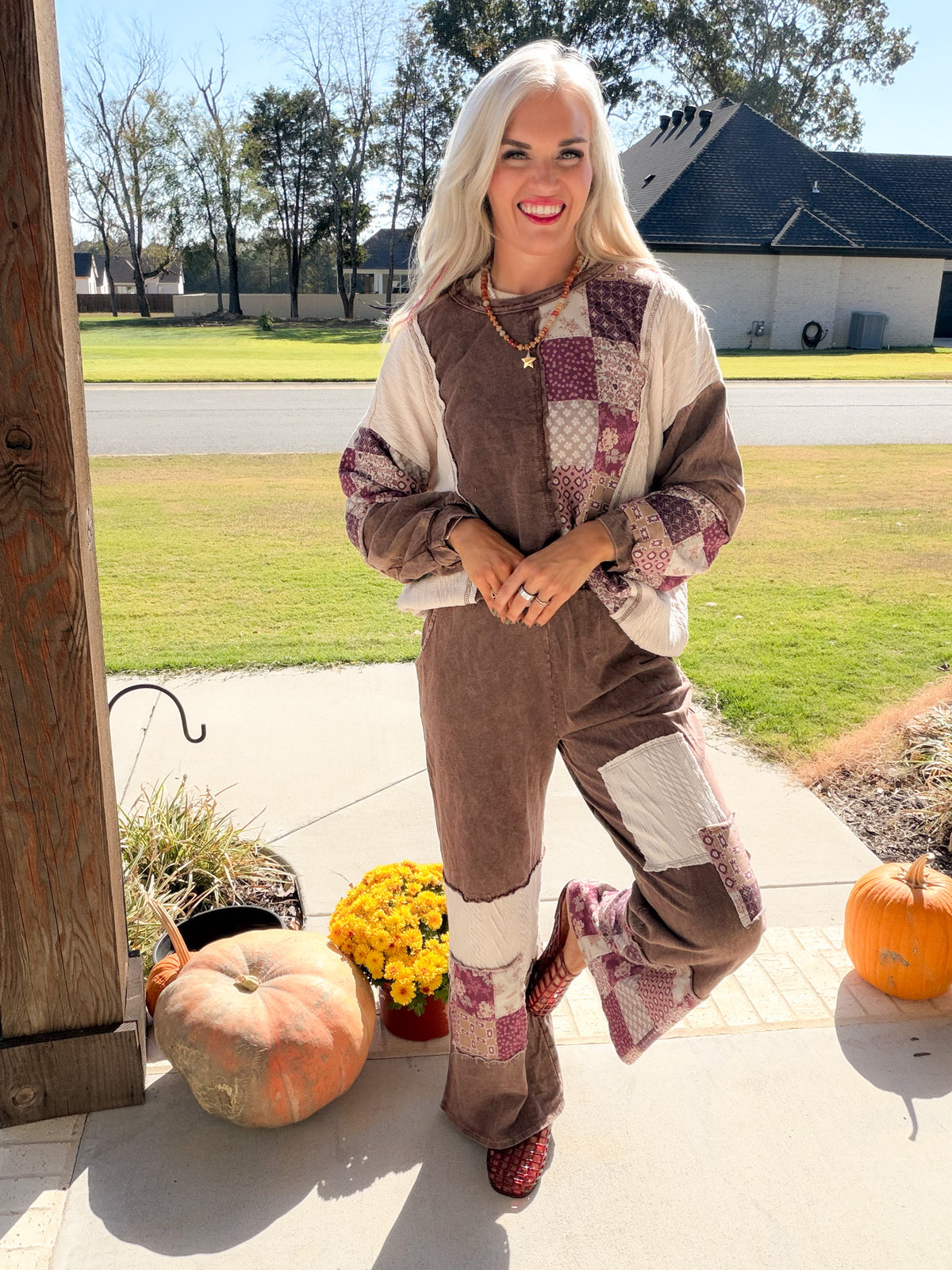 Chocolate paisley patchwork pants and matching sweatshirt shown on a model with one knee bent.