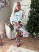 Women's relaxed fit striped jeans shown with one leg bent, styled with a cream sweatshirt and woven mules.