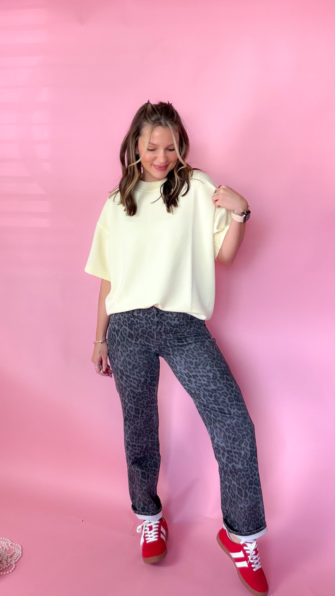woman standing against pink background showcasing the women's silver leopard jeans