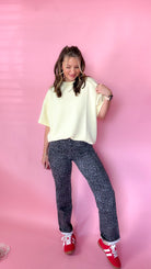woman standing against pink background showcasing the women's silver leopard jeans