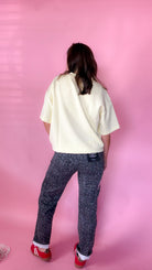 woman standing against pink background showcasing the women's silver leopard jeans- back view