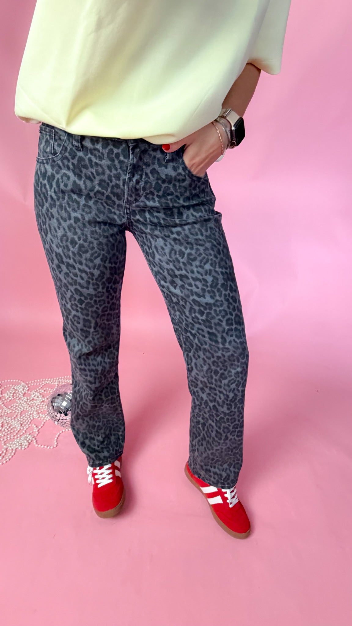 woman standing against pink background showcasing the women's silver leopard jeans