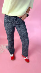 woman standing against pink background showcasing the women's silver leopard jeans