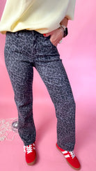 woman standing against pink background showcasing the women's silver leopard jeans - close up
