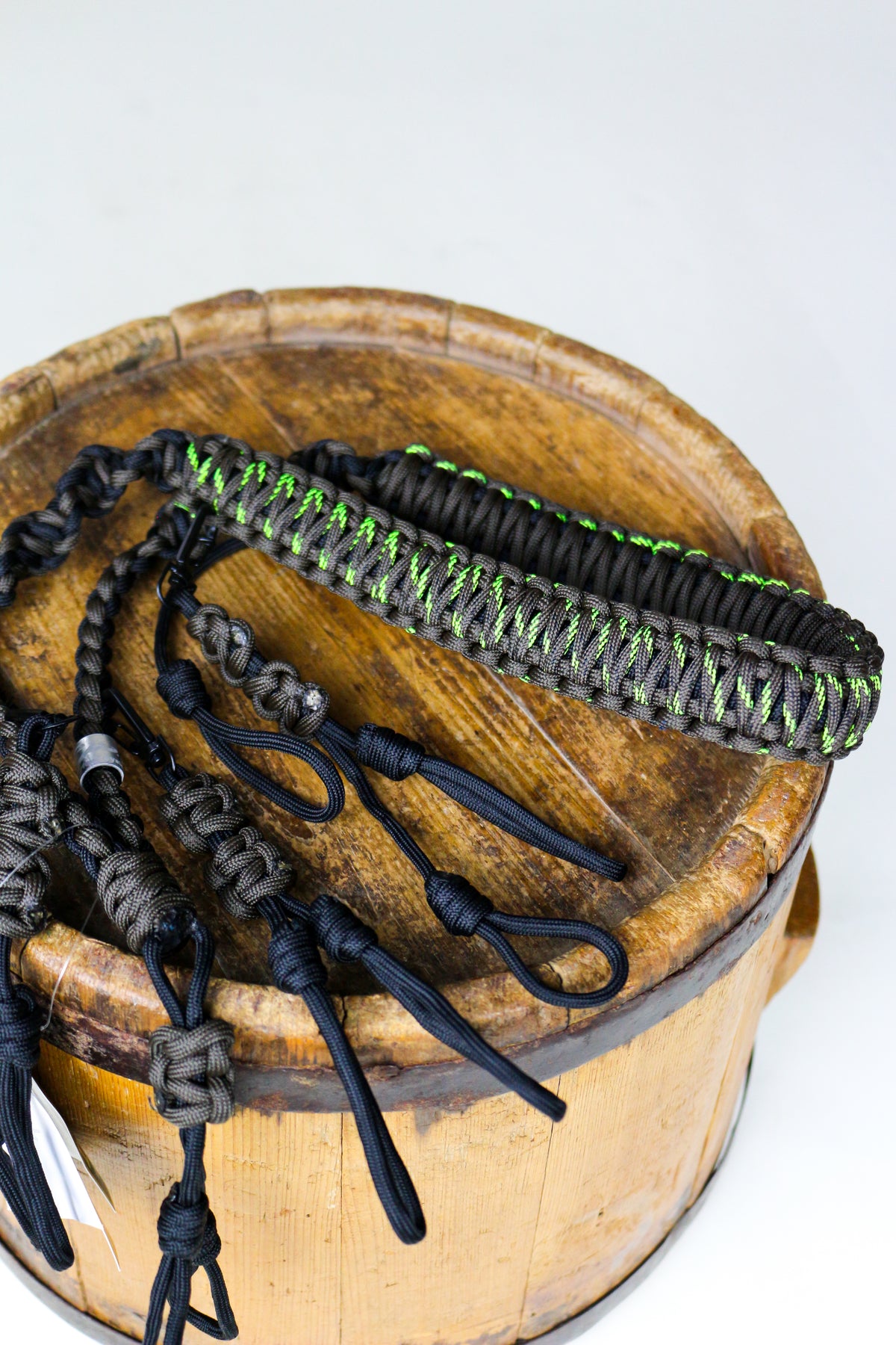 Drake Paracord Black and Olive Duck Caller's Lanyard coiled on a wooden barrel