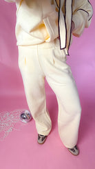 woman standing against pink background with yellow hoodie and sweatpants matching set