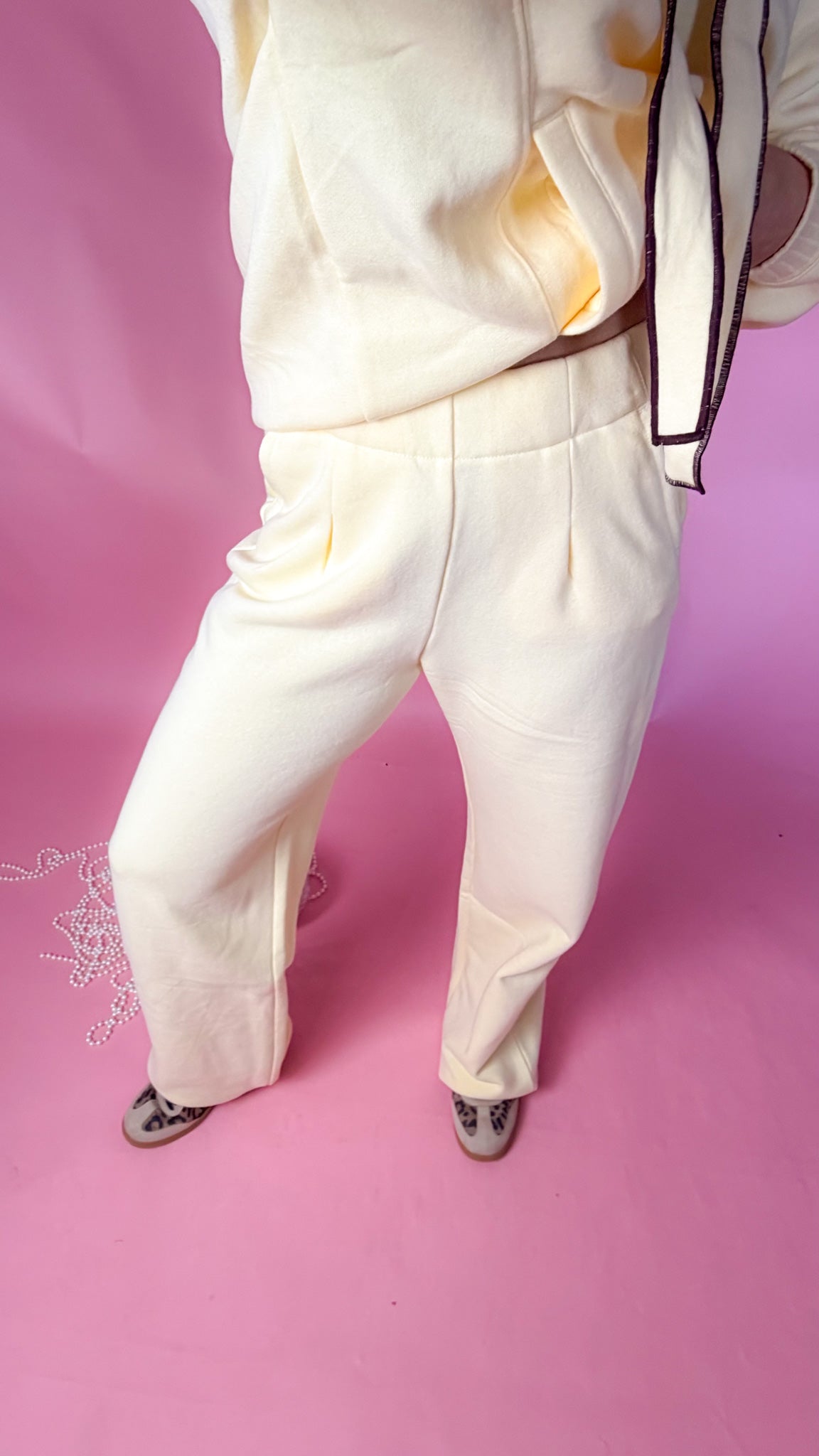 woman standing against pink background with yellow hoodie and sweatpants matching set