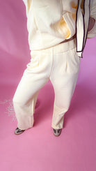 woman standing against pink background with yellow hoodie and sweatpants matching set