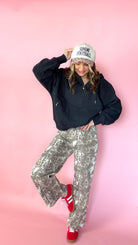 woman picturing black half zip pullover with leopard trucker hat and snake print jeans.