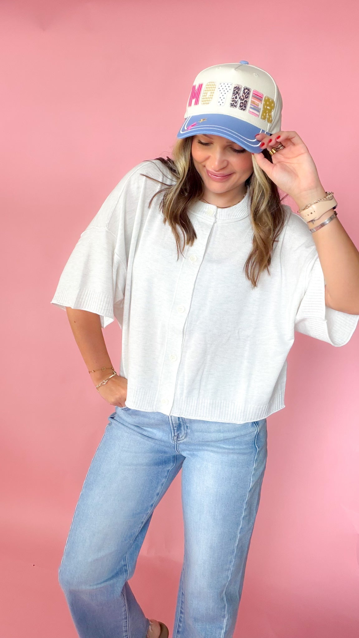 woman picturing short sleeve button up top against a pink background