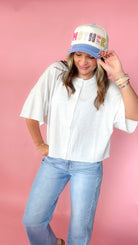 woman picturing short sleeve button up top against a pink background