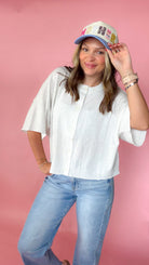 woman picturing short sleeve button up top against a pink background