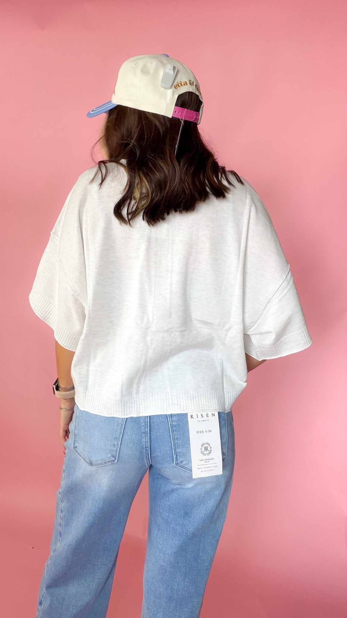 woman picturing short sleeve button up top against a pink background