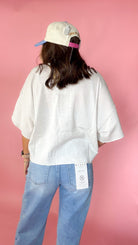 woman picturing short sleeve button up top against a pink background