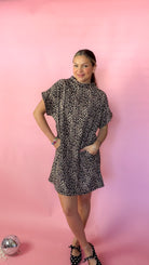 lady with hands in pockets of the dress standing against pink background