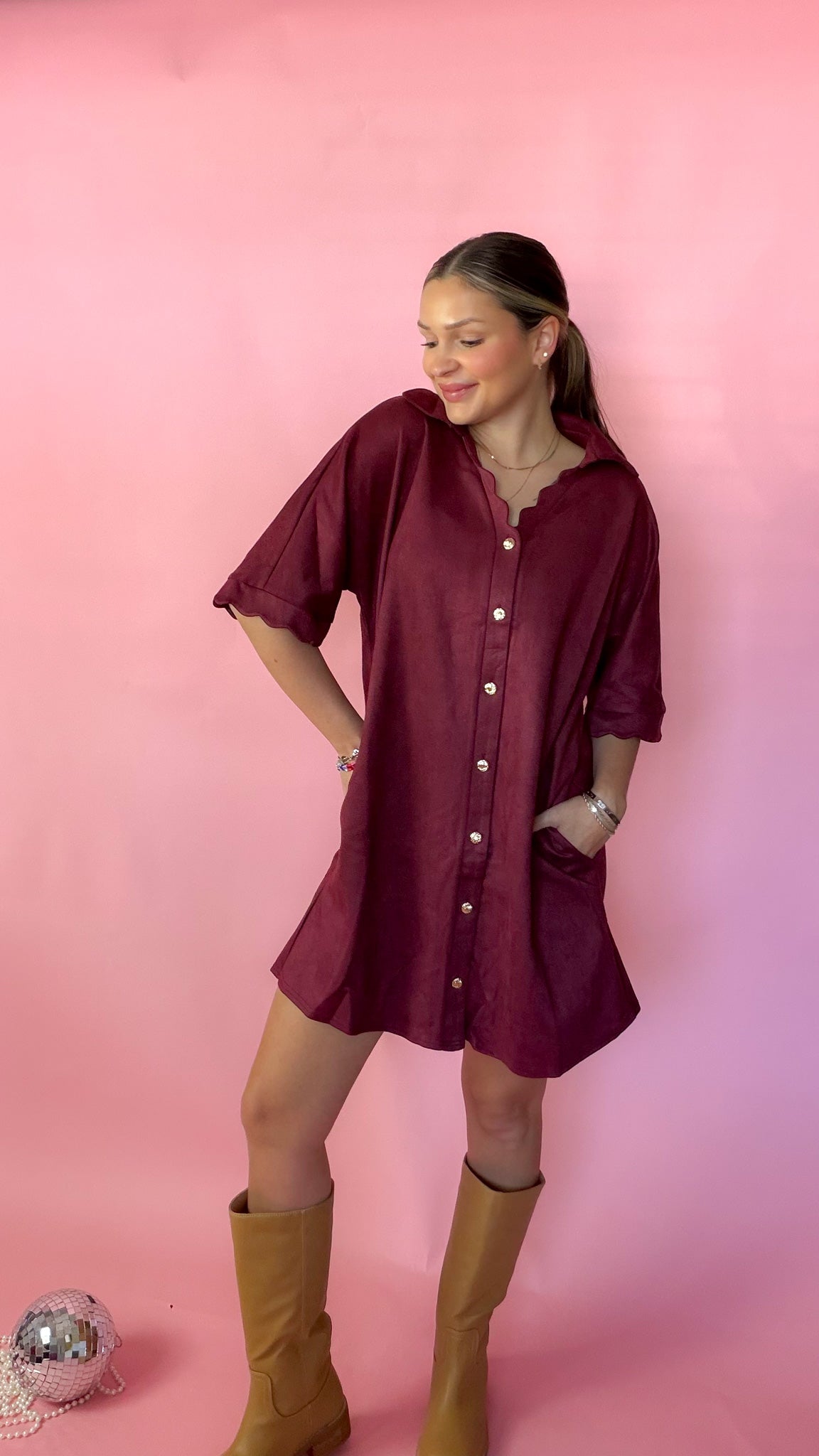 HK paired the dress with boots and is standing against a pink background