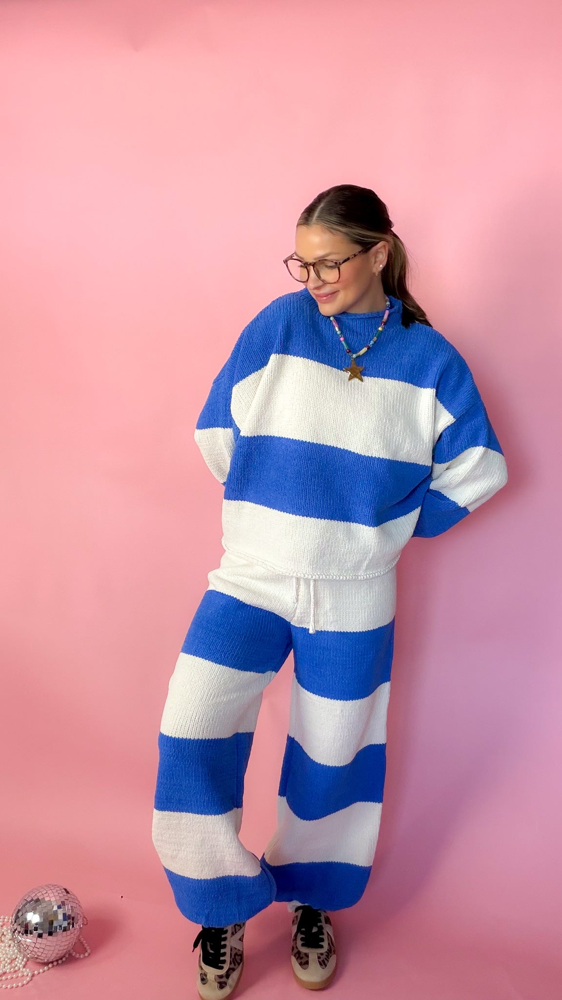 woman wearing blue stripe knit sweater against pink background