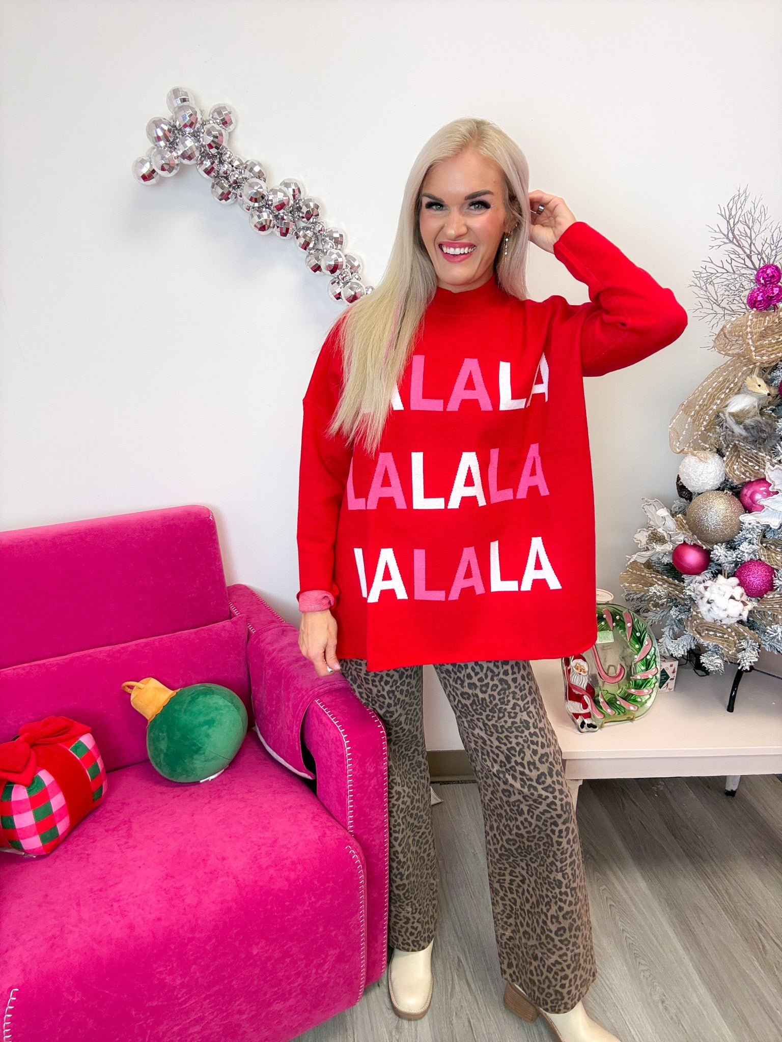 Mud Pie red FA LA LA jacquard Christmas sweater worn with leopard pants, front view