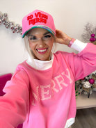 Smiling woman wearing the pink So Very Merry Christmas trucker hat