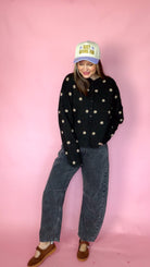 At A Glance black polka dot sweater, front view with hands in pockets