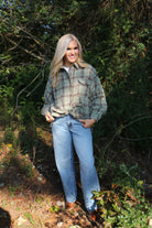 Woman wearing a plaid shirt and jeans standing in a forested area