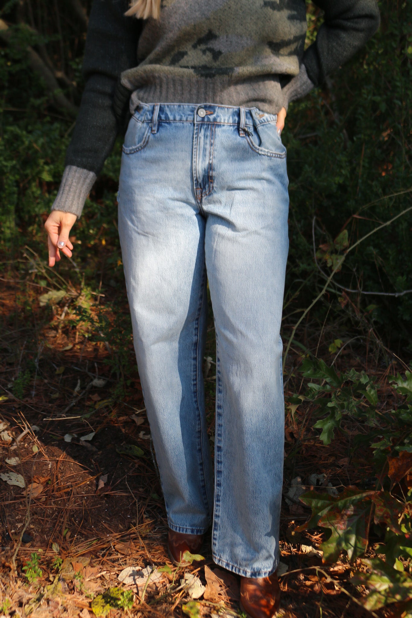 Person wearing blue jeans standing in a forest setting