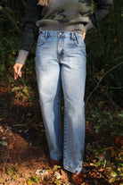 Person wearing blue jeans standing in a forest setting