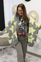 Person wearing a gray and yellow star-patterned cardigan in an indoor setting.