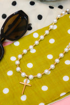 Lolly Pearl Beaded Gold Cross Necklace on green polka dot fabric with sunglasses