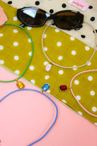 Quin Pendant Necklace, all four cord colors with gem pendants spread on green dot fabric