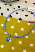 Quin Pendant Necklace in blue cord with blue emerald-cut jewel pendant on dot fabric
